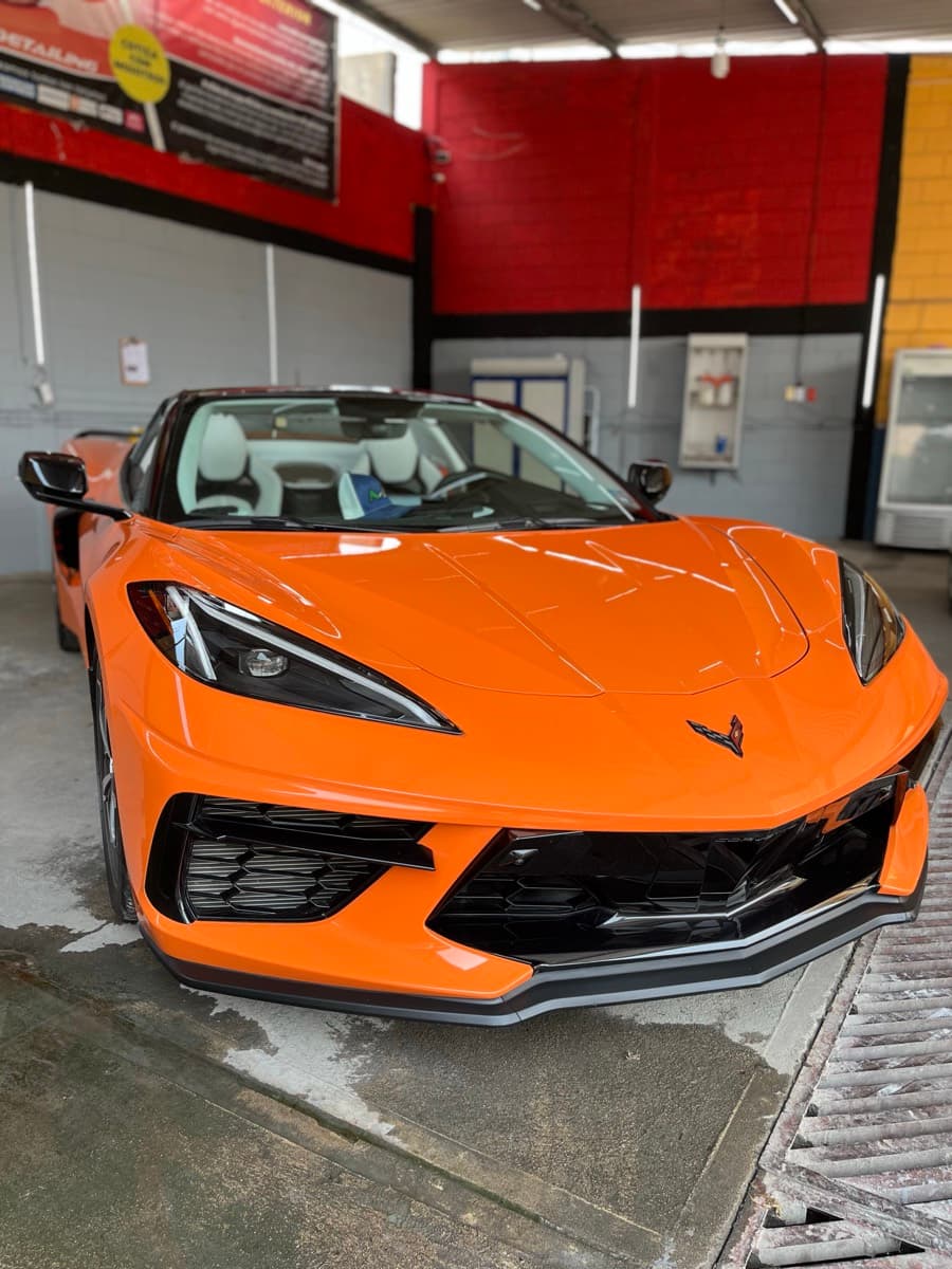 Chevrolet Corvette naranja de frente dentro del taller de Minas