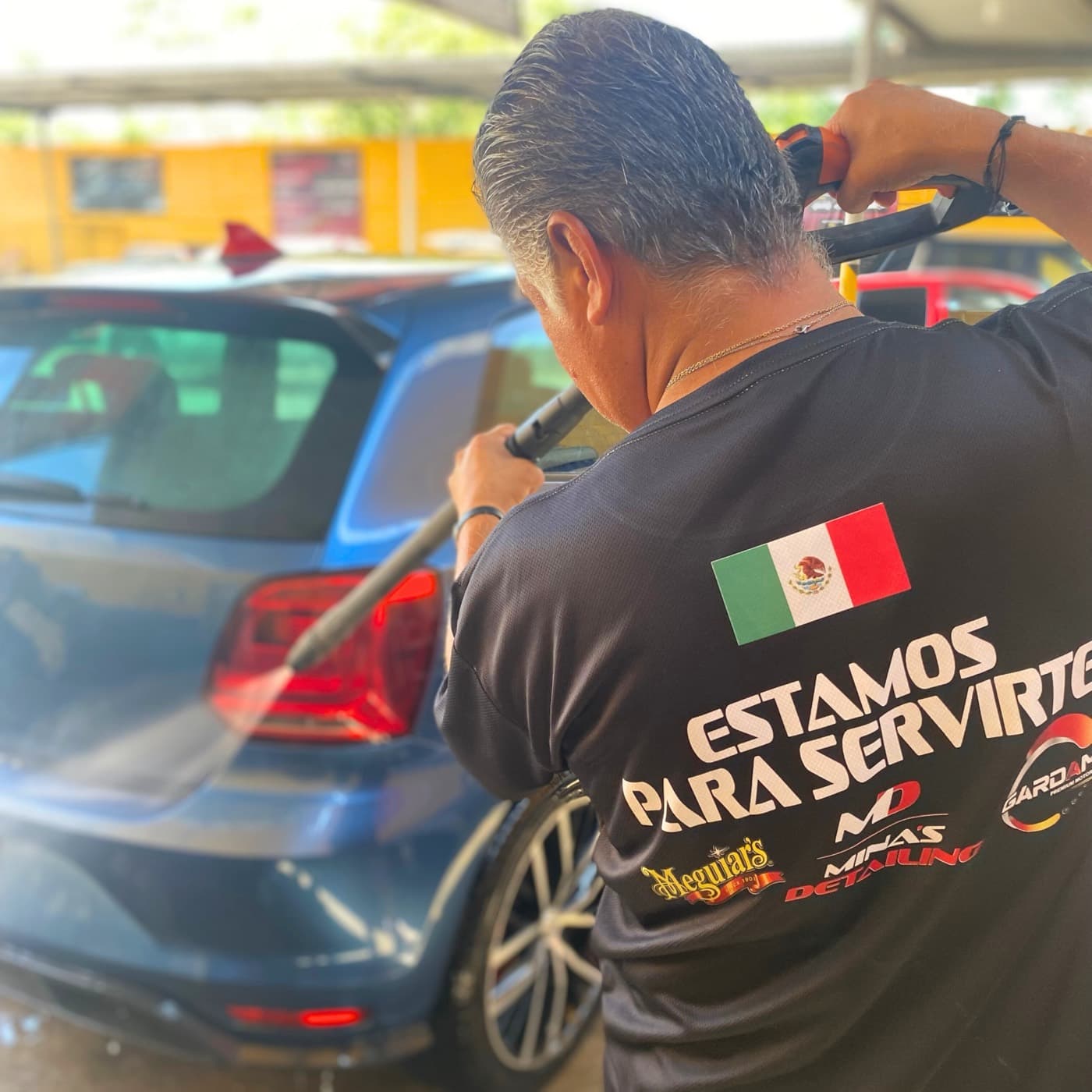 Un integrante del equipo de Minas Detailing lavando un auto en el taller